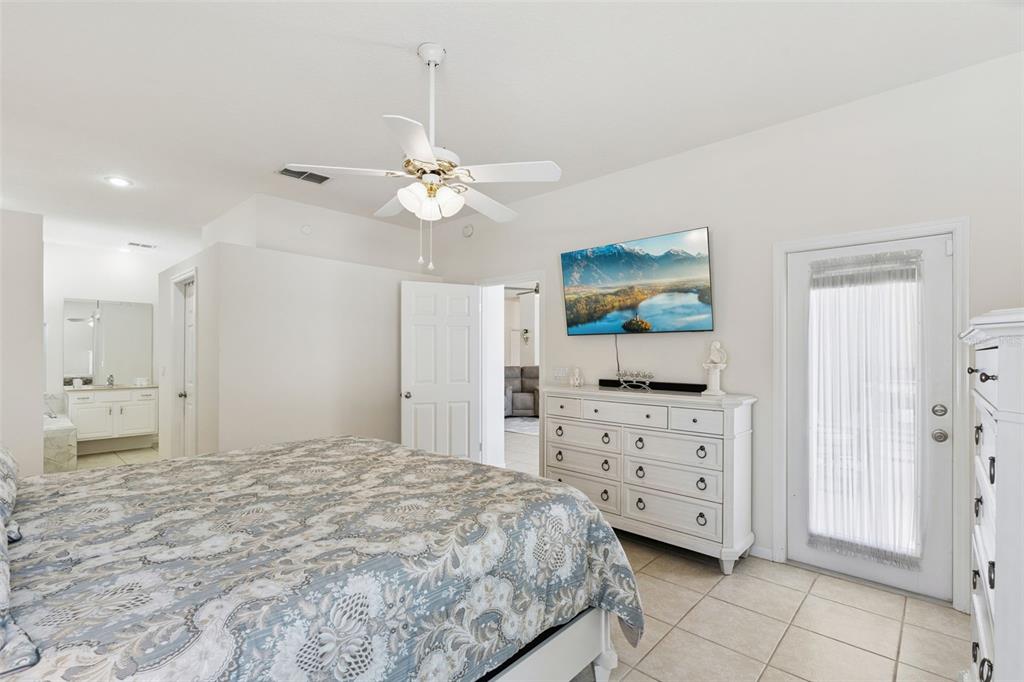 13319 Via Roma Circle Clermont, FL 34711 - Photo 19 of 43 a spacious bedroom with a bed and a chandelier