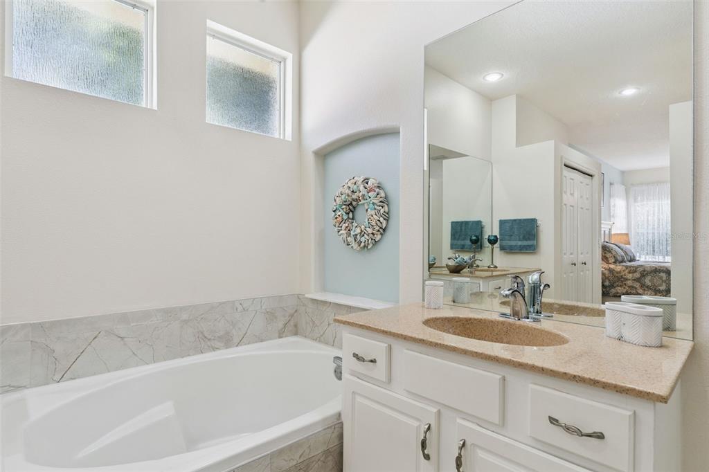 13319 Via Roma Circle Clermont, FL 34711 - Photo 22 of 43 a bathroom with a granite countertop sink a mirror a vanity and bathtub