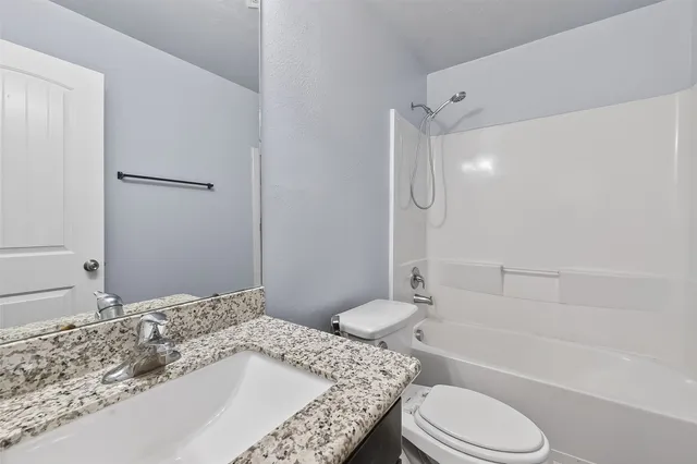 a bathroom with a granite countertop sink toilet tub and shower