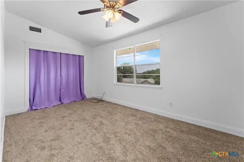 an empty room with windows and ceiling fan