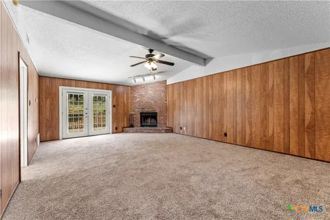 an empty room with windows and fireplace
