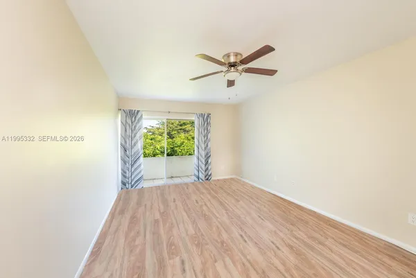 a view of a big room with wooden floor a ceiling fan and windows