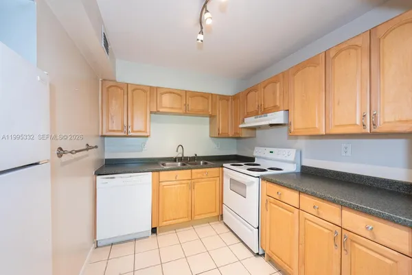 a kitchen with stainless steel appliances granite countertop a sink stove refrigerator and cabinets