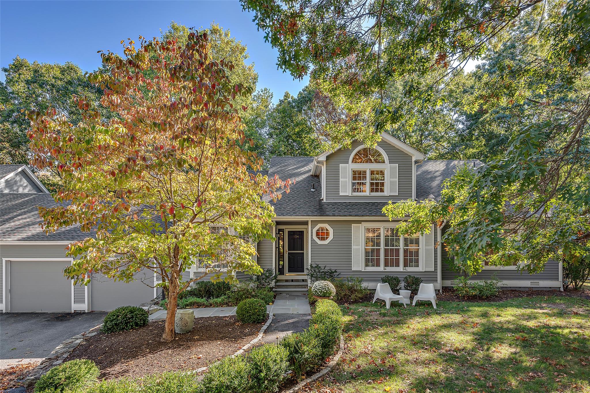 a view of a yard in front of a brick house with large windows