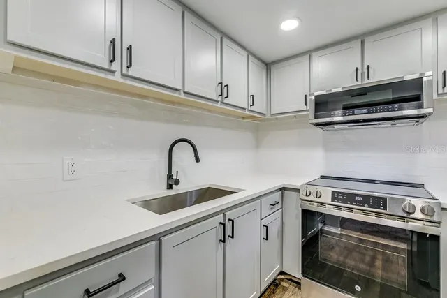 a kitchen with stainless steel appliances granite countertop a sink a stove and cabinets