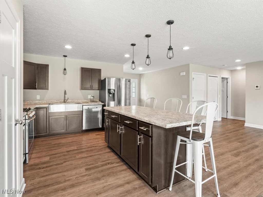5525 White Road Geneva, OH 44041 - Photo 9 of 28 Kitchen with stainless steel appliances, pendant lighting, sink, a center island, and light hardwood / wood-style flooring