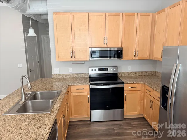 a kitchen with stainless steel appliances granite countertop a stove a sink and a microwave