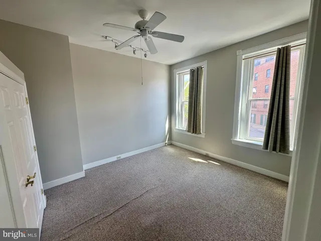 an empty room with windows and fan