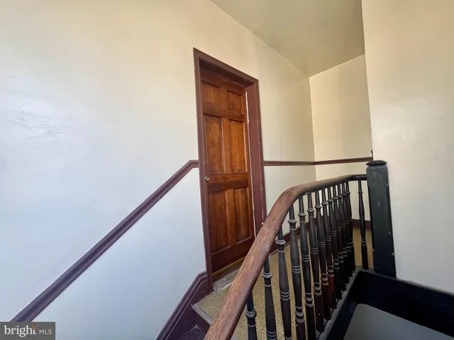 a view of staircase with wooden floor and white walls
