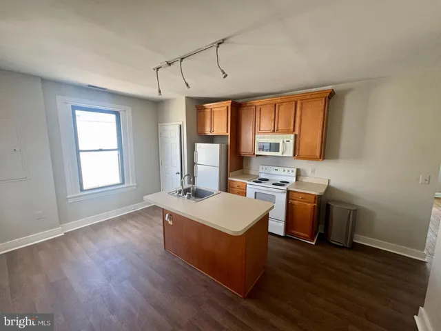 a living room with stainless steel appliances granite countertop wooden floors and sink