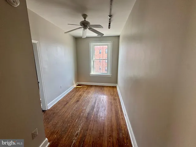 a view of empty room with wooden floor and fan
