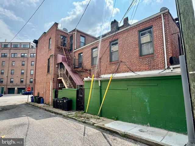 a view of a brick house with a yard plants and a large tree