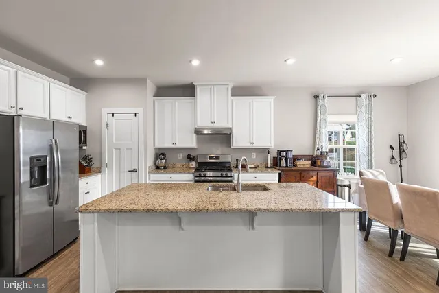 a large kitchen with granite countertop a large counter top stainless steel appliances and cabinets