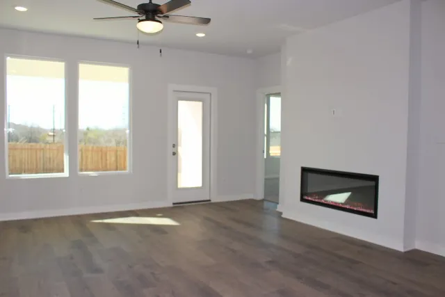 an empty room with wooden floor fan and windows