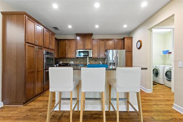 a kitchen with stainless steel appliances refrigerator dining table and chairs
