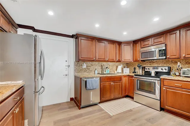 a kitchen with stainless steel appliances granite countertop a refrigerator and a stove top oven