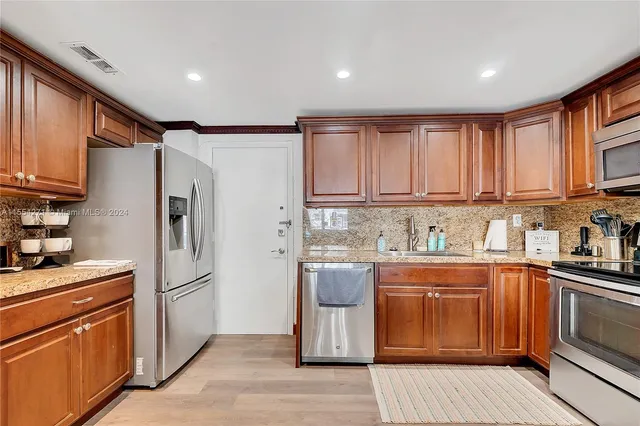 a kitchen with stainless steel appliances granite countertop a refrigerator sink and cabinets