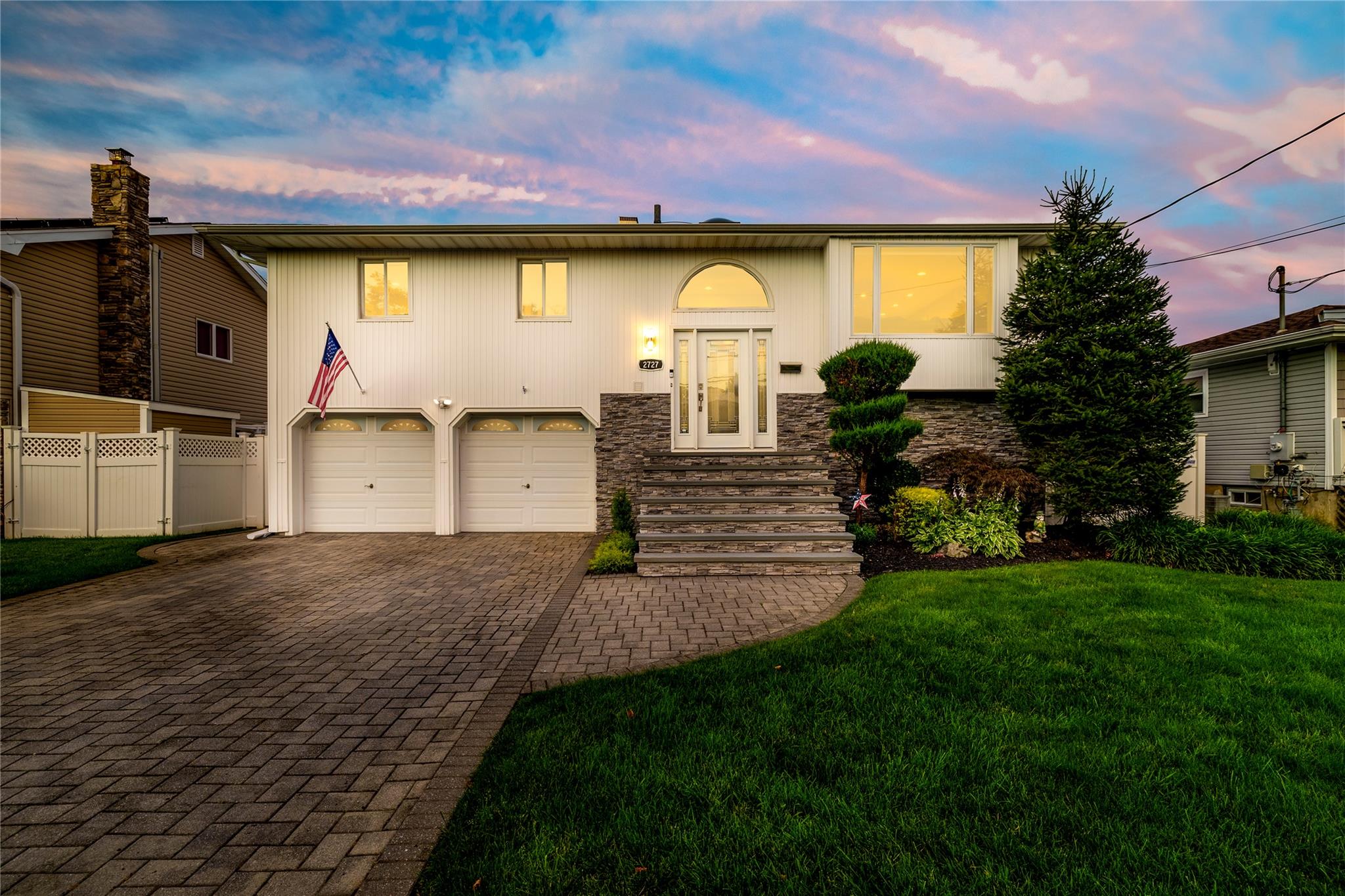 2727 Mandalay Beach Road Wantagh, NY 11793 - Photo 1 of 1 View of front facade with decorative driveway, an attached garage, and stone siding