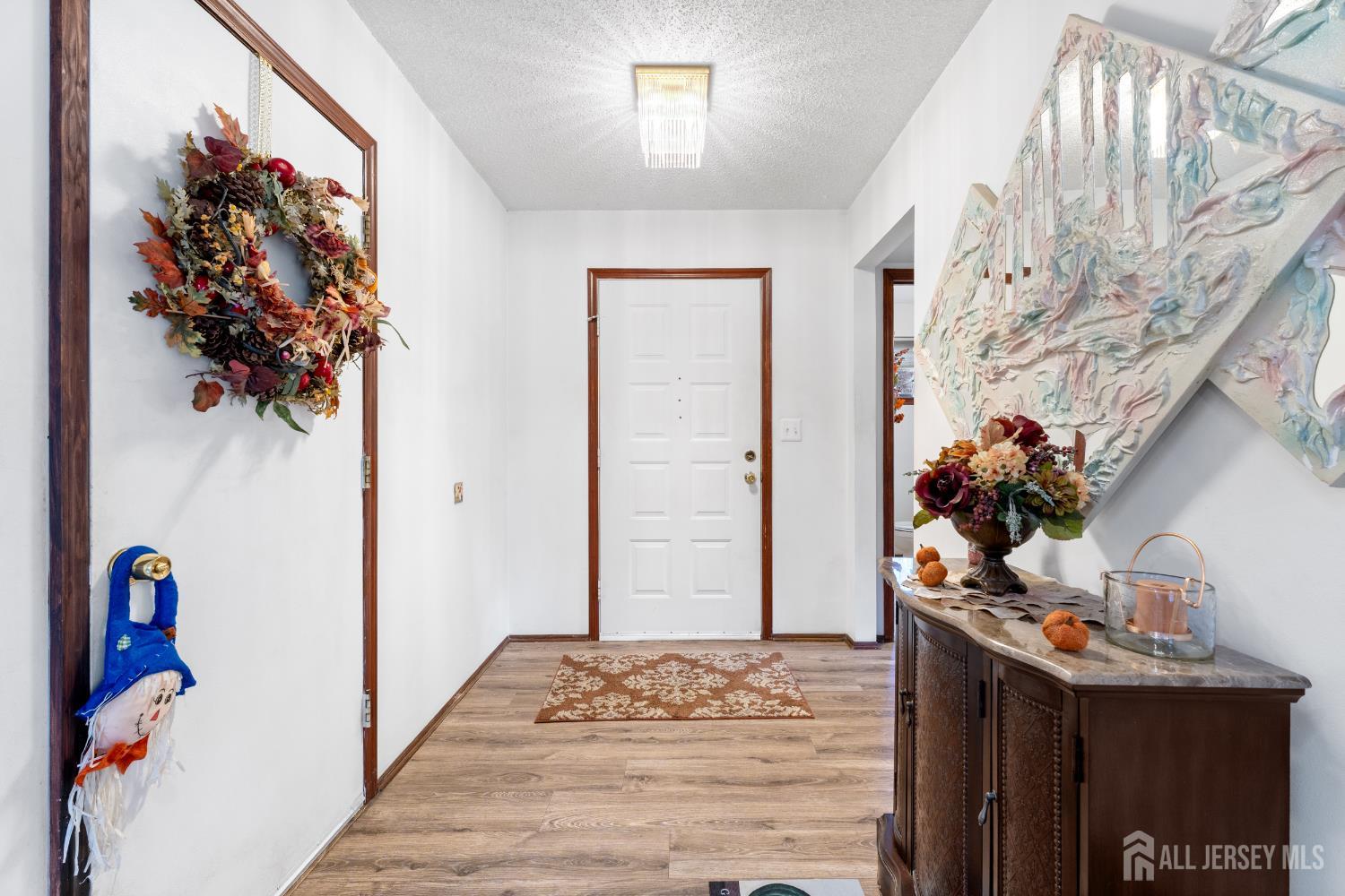 236 Community Circle Old Bridge, NJ 08857 - Photo 9 of 46 a view of a hallway to a livingroom with wooden floor and a chandelier