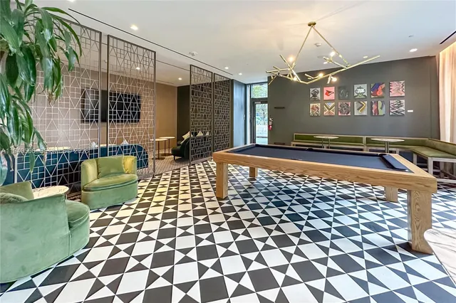 a living room with a black white checkered floor with a gaming machine and dining chairs