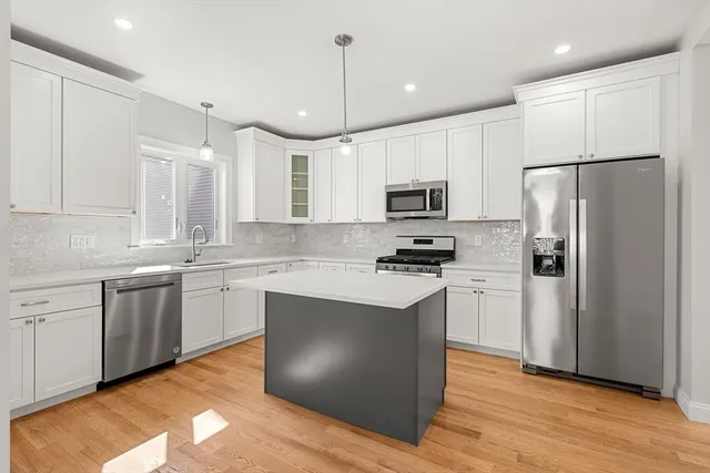 a kitchen with kitchen island granite countertop appliances cabinets sink and a counter top space
