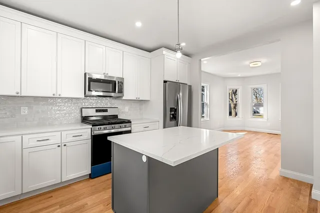 a kitchen with stainless steel appliances a refrigerator a stove a sink and white cabinets
