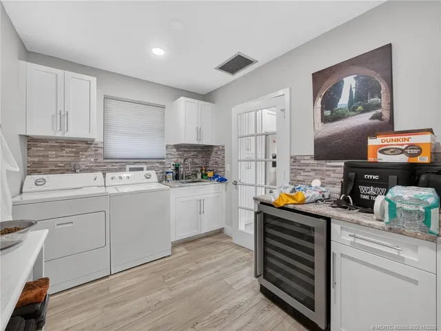 a kitchen with stainless steel appliances a stove top oven a sink a refrigerator white cabinets and wooden floor