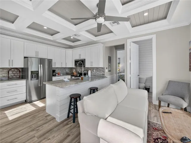 a living room with stainless steel appliances furniture and a kitchen view
