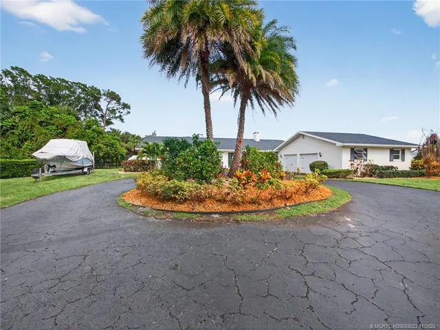 a view of a swimming pool with a yard and palm trees