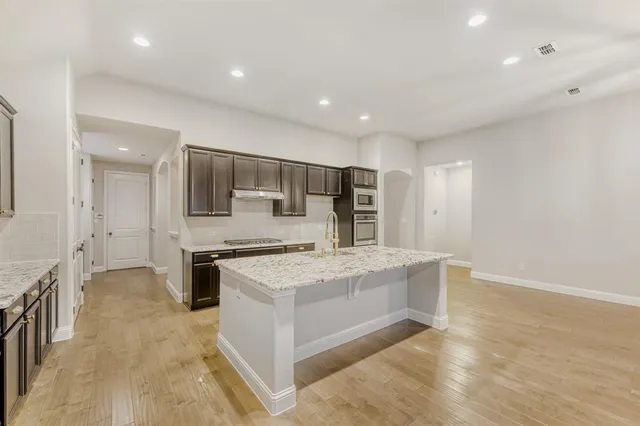 a large white kitchen with a stove a sink a refrigerator and white cabinets