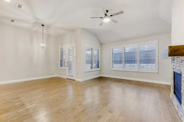 a view of an empty room with a window and wooden floor