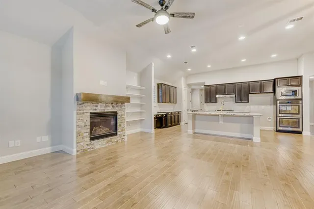 a view of kitchen with kitchen island a sink counter top space appliances and a ceiling fan