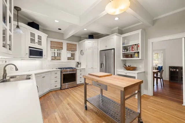 a large kitchen with stainless steel appliances granite countertop a stove oven and a refrigerator with white cabinets