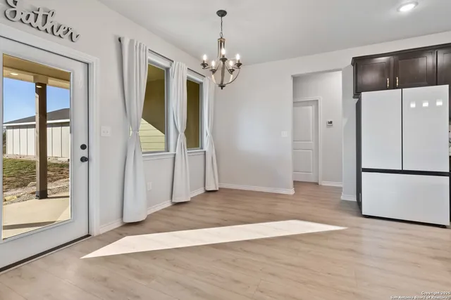 a view of a hallway with wooden floor and a chandelier