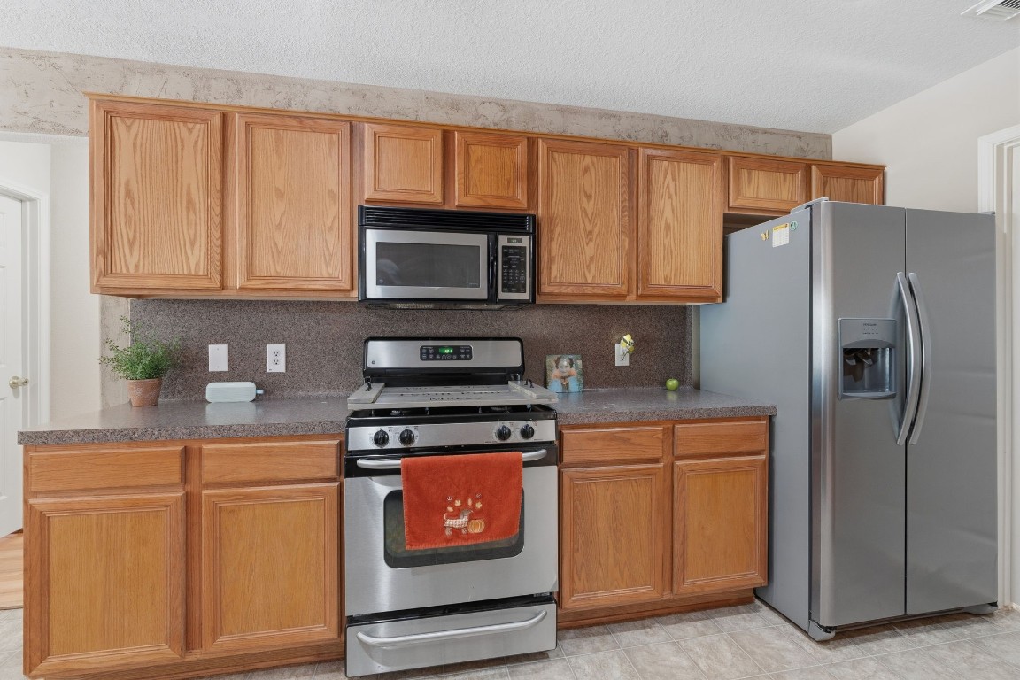 907 Columbia River Road Montgomery, TX 77316 - Photo 10 of 34 a kitchen with granite countertop a refrigerator stove and microwave