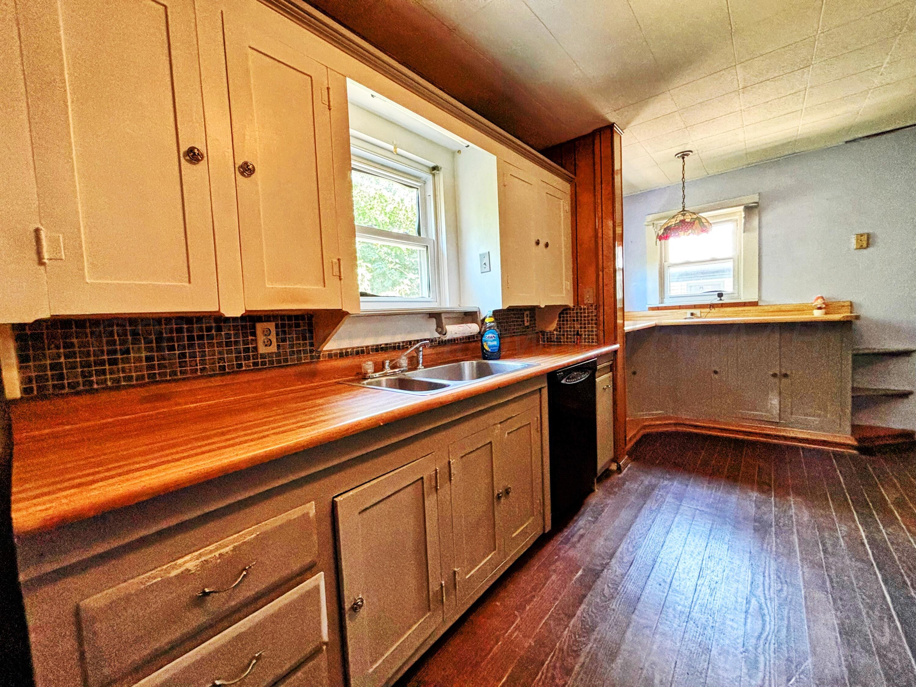 522 South Baylor Street Perryton, TX 79070 - Photo 23 of 52 a kitchen with stainless steel appliances a sink dishwasher a stove and white cabinets with wooden floor