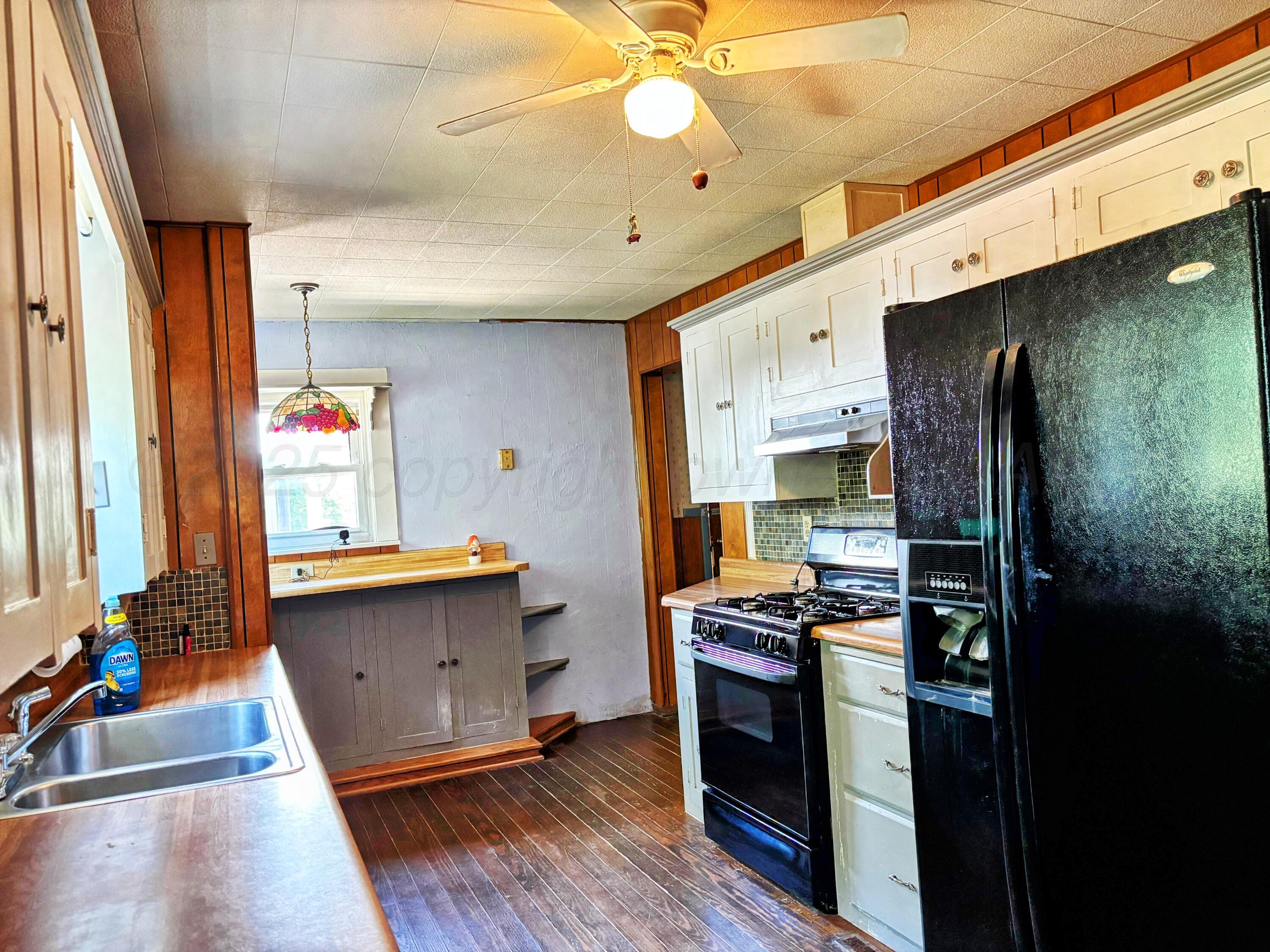 522 South Baylor Street Perryton, TX 79070 - Photo 24 of 52 a kitchen with stainless steel appliances kitchen island granite countertop a refrigerator a stove and a wooden floor