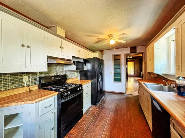 a kitchen with granite countertop a sink a stove and refrigerator
