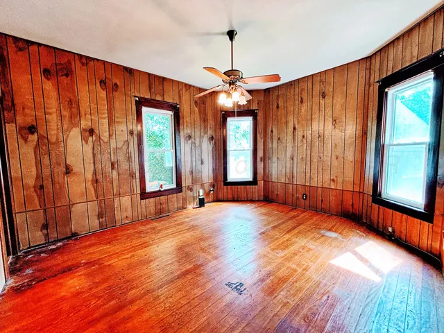 an empty room with wooden floor and windows