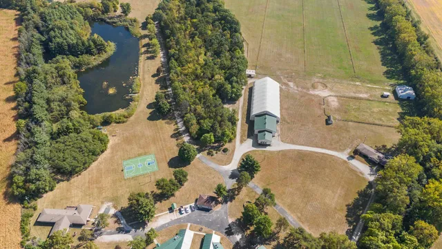 an aerial view of residential house with outdoor space and trees all around