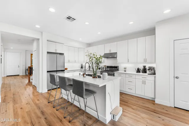 a kitchen with kitchen island granite countertop a sink cabinets and wooden floor