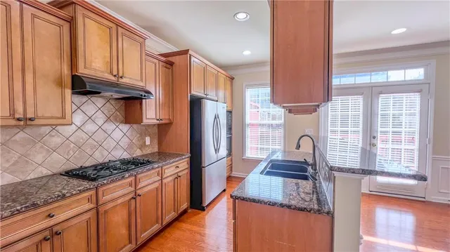 a kitchen with granite countertop a stove a sink and a refrigerator