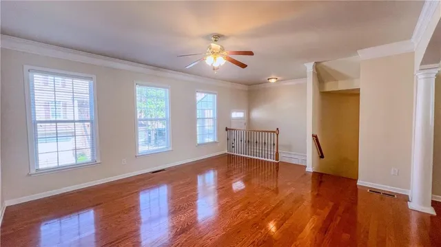 a view of an empty room with wooden floor and a window