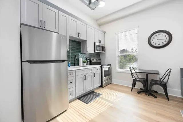 a kitchen with stainless steel appliances granite countertop a refrigerator a stove a sink and a refrigerator with wooden floor