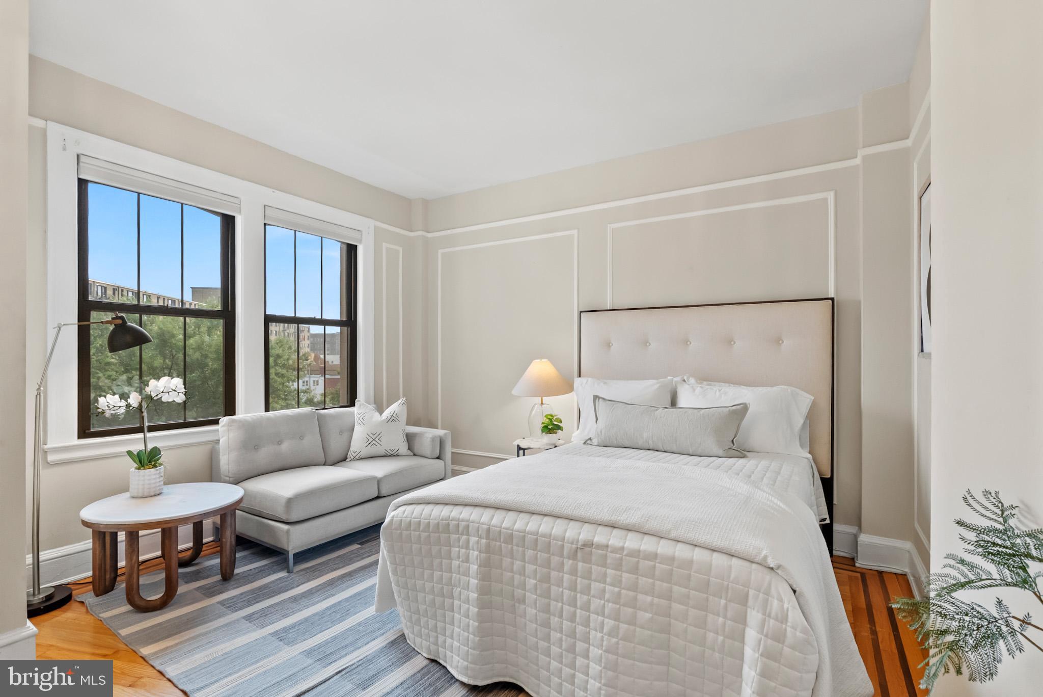 a bedroom with a bed a large window and couch