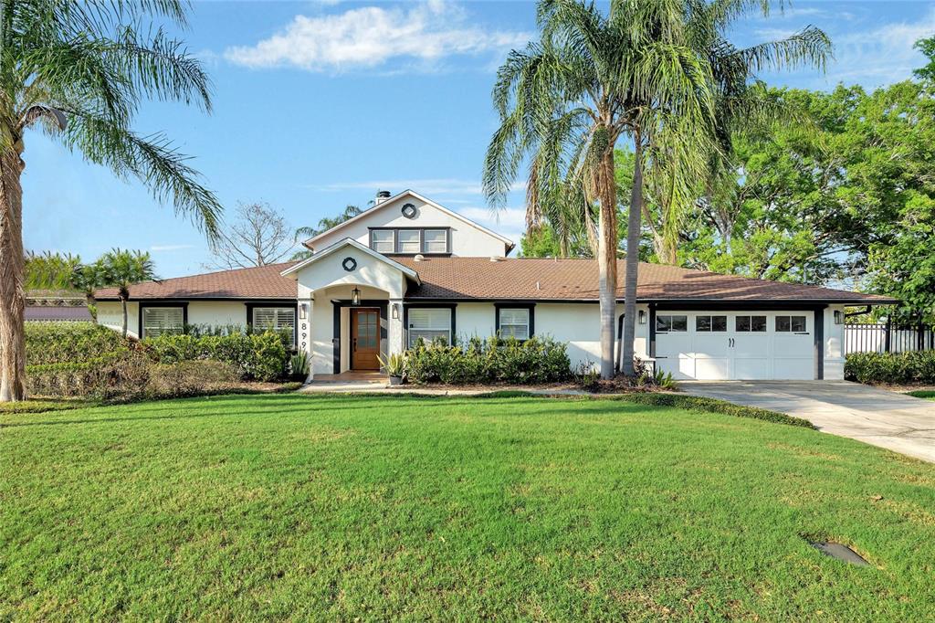 a front view of a house with a garden and trees