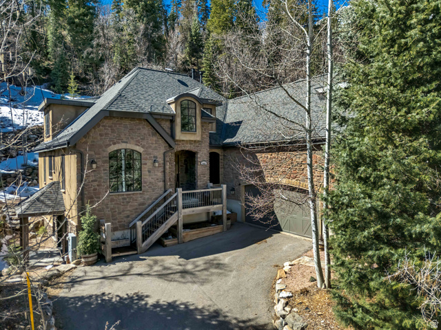 9049 Timphaven Road Sundance, UT 84604 - Photo 3 of 63 View of front facade featuring stone siding, a shingled roof, driveway, and a garage