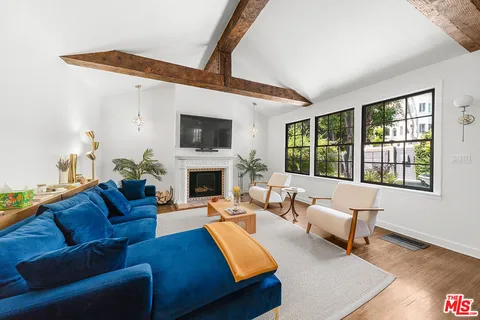 a living room with furniture kitchen view and a wooden floor