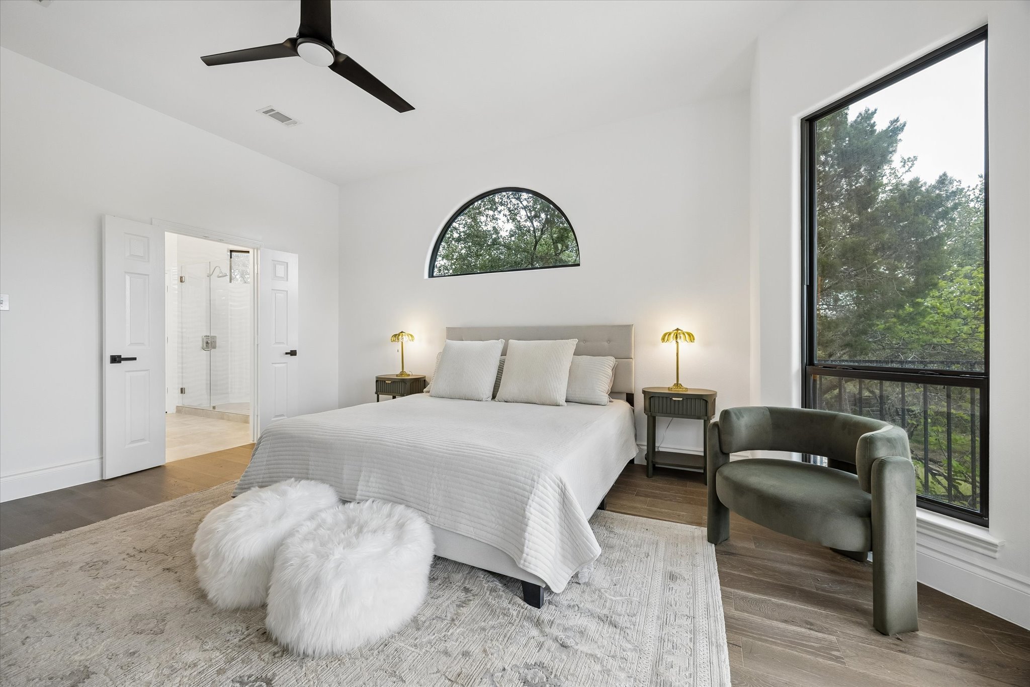 3719 Bee Creek Road Spicewood, TX 78669 - Photo 15 of 40 Hardwood floors and tall windows define this inviting bedroom, featuring an arched window above the bed.