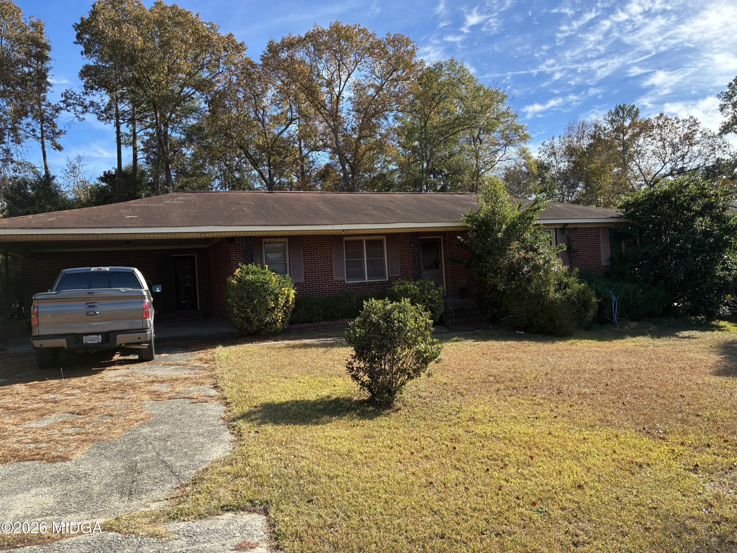 a front view of a house with yard outdoor seating and covered with trees